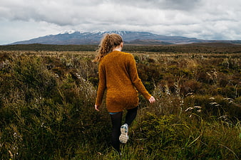 Woman hiking in moorland with snow-capped mountains
