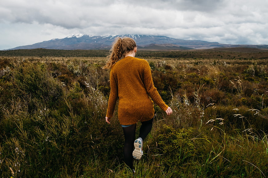 Woman hiking in moorland with snow-capped mountains
