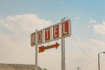 Vintage Retro Motel Sign with Arrow Against Blue Sky