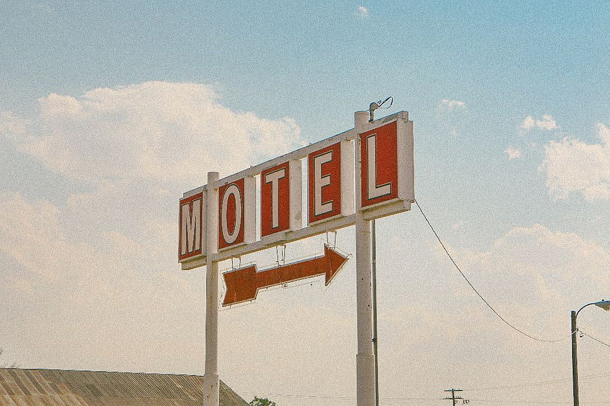 Vintage Retro Motel Sign with Arrow Against Blue Sky