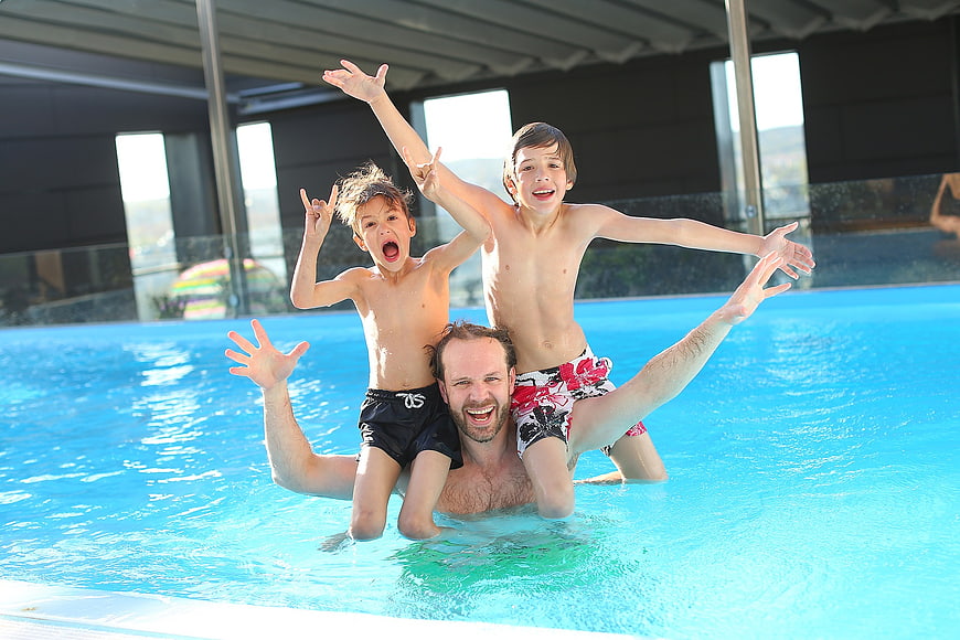 Happy Father and Two Boys Playing in Indoor Swimming Pool