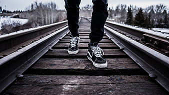 Person Walking on Train Tracks in Winter Sneakers