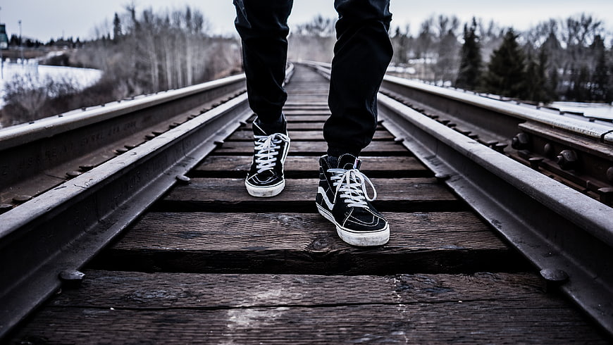 Person Walking on Train Tracks in Winter Sneakers