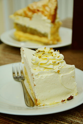 Slice of Cream Cake with Pistachio Topping on White Plate