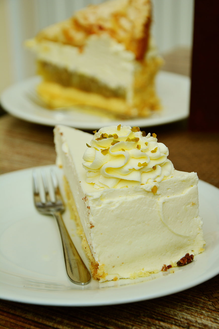 Slice of Cream Cake with Pistachio Topping on White Plate