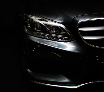 Close-up of sleek black luxury car headlight and grille