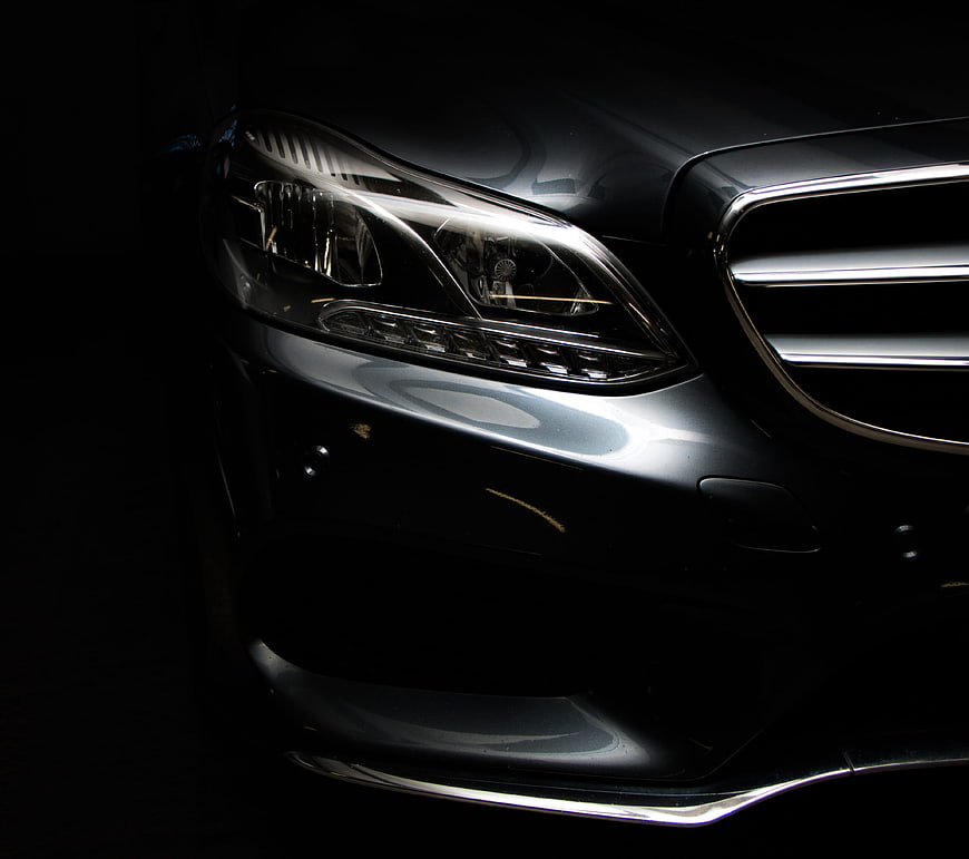 Close-up of sleek black luxury car headlight and grille
