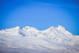 Snow-covered mountain peaks under a clear blue sky