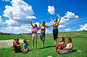 Happy Asian children jumping and playing in green meadow