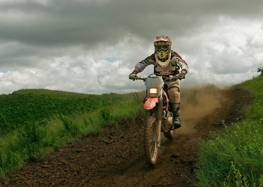 Motocross Rider On Dirt Trail In Green Countryside