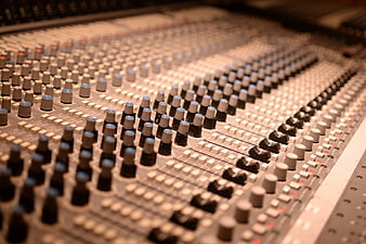 Close-up of professional audio mixing console with knobs and sliders