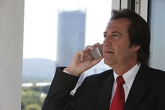 Businessman in Suit Talking on Mobile Phone by Window