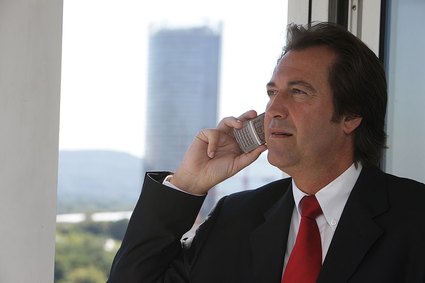 Businessman in Suit Talking on Mobile Phone by Window