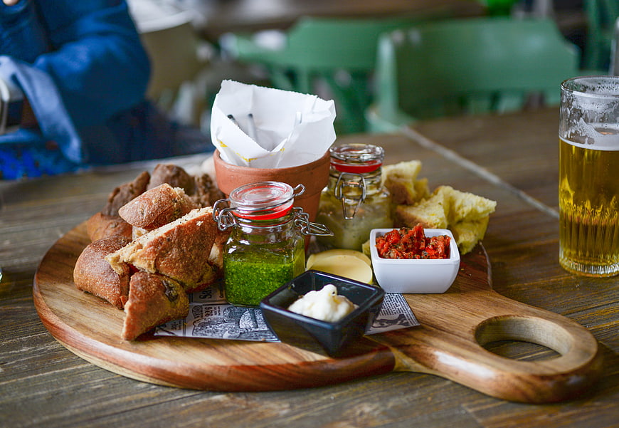 Rustic bread platter with dips and beer on wooden table