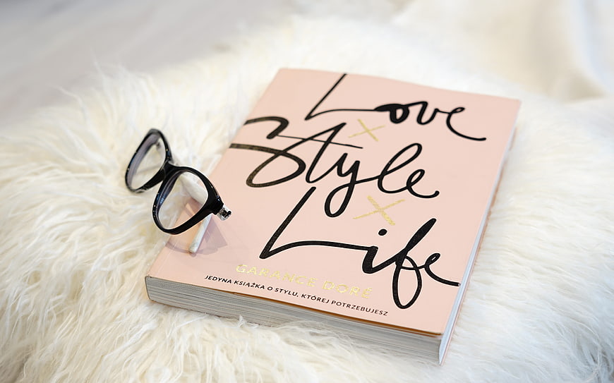Pink book with glasses on white fur background