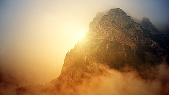 Majestic Mountain Peak Emerging Through Golden Morning Fog
