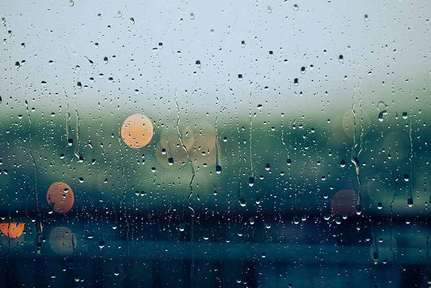 Raindrops on Window Glass with Blurred Bokeh Lights
