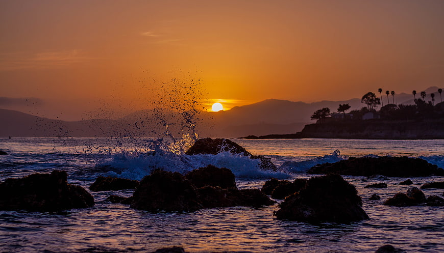 Dramatic Ocean Sunset with Splashing Waves on Rocks