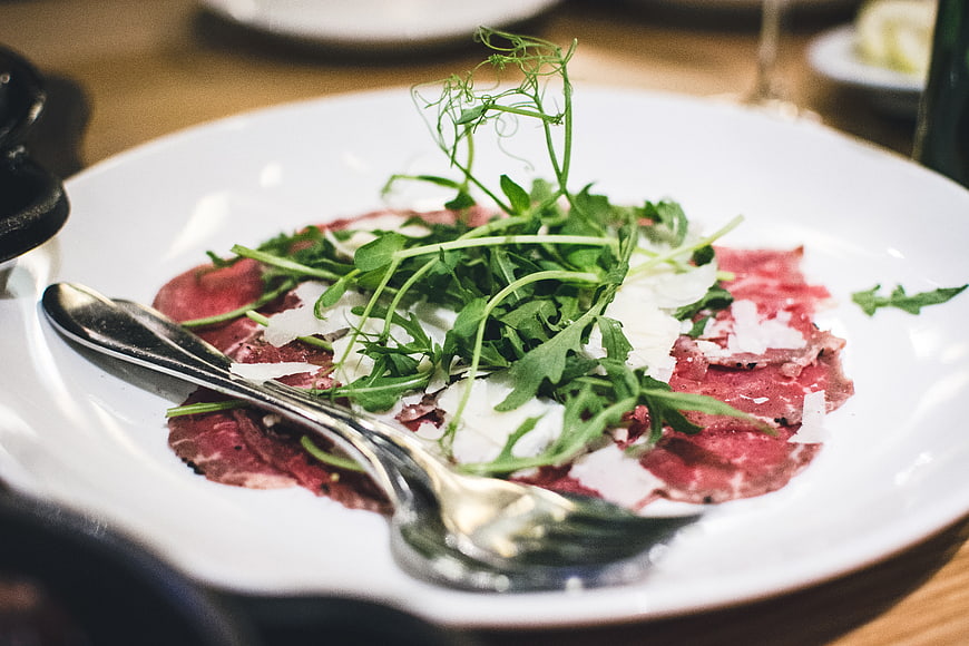 Bresaola Carpaccio with Arugula and Parmesan on White Plate