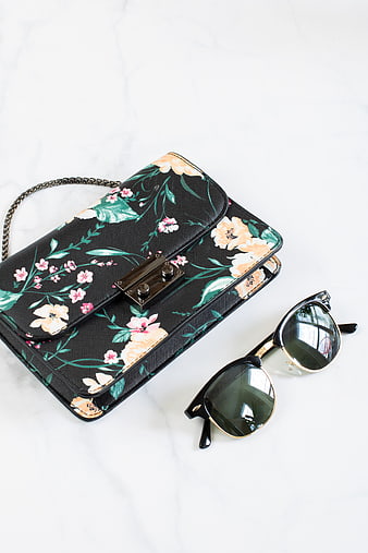Floral black handbag and sunglasses on marble background