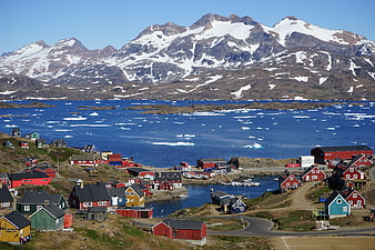 Colorful houses in Tasiilaq, Greenland with snowy mountains and icebergs