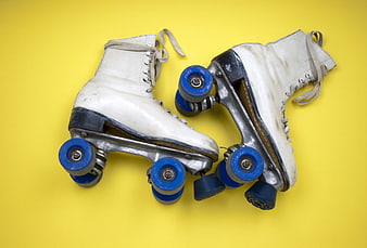 Vintage White Roller Skates with Blue Wheels on Yellow Background