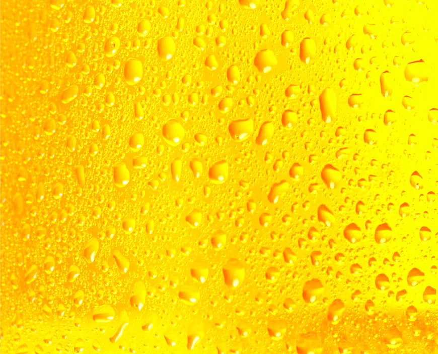 Close-up of condensation droplets on a cold yellow beverage
