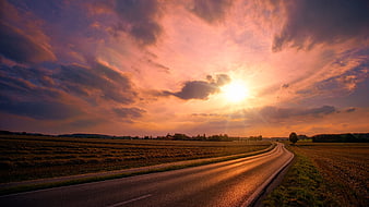 Dramatic Sunset Over Rural Road and Harvested Fields