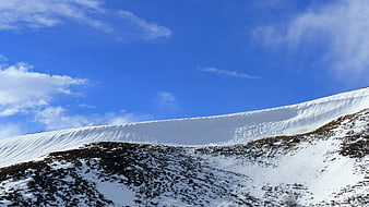 Snowy Mountain Slope Under Blue Sky