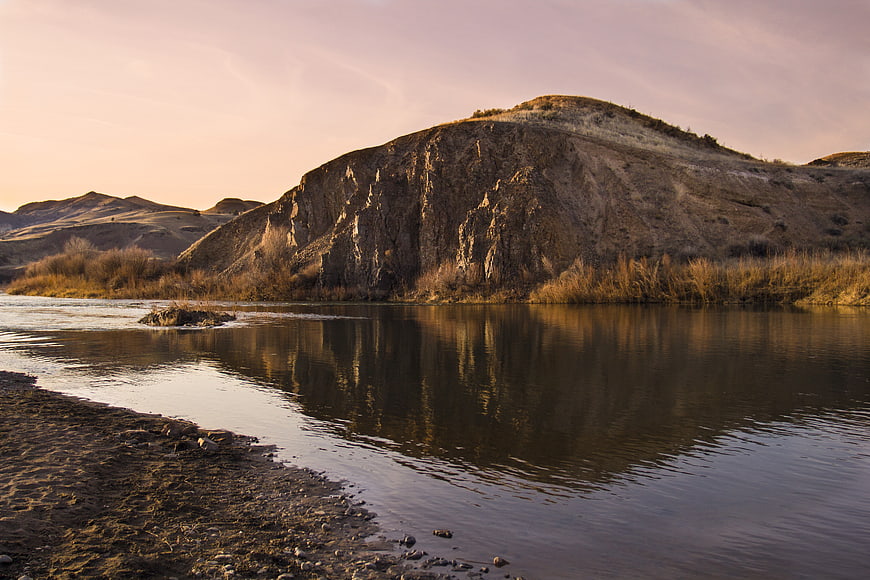 Serene River Landscape with Rocky Cliff at Sunset