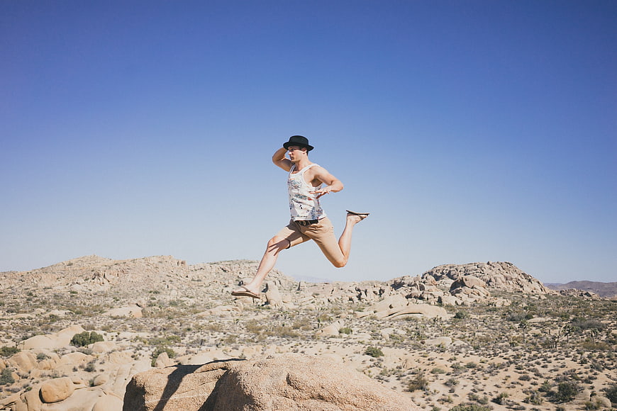 Man jumping in desert landscape with blue sky