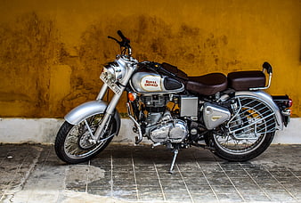 Silver Royal Enfield Classic 350 Motorcycle Against Yellow Wall