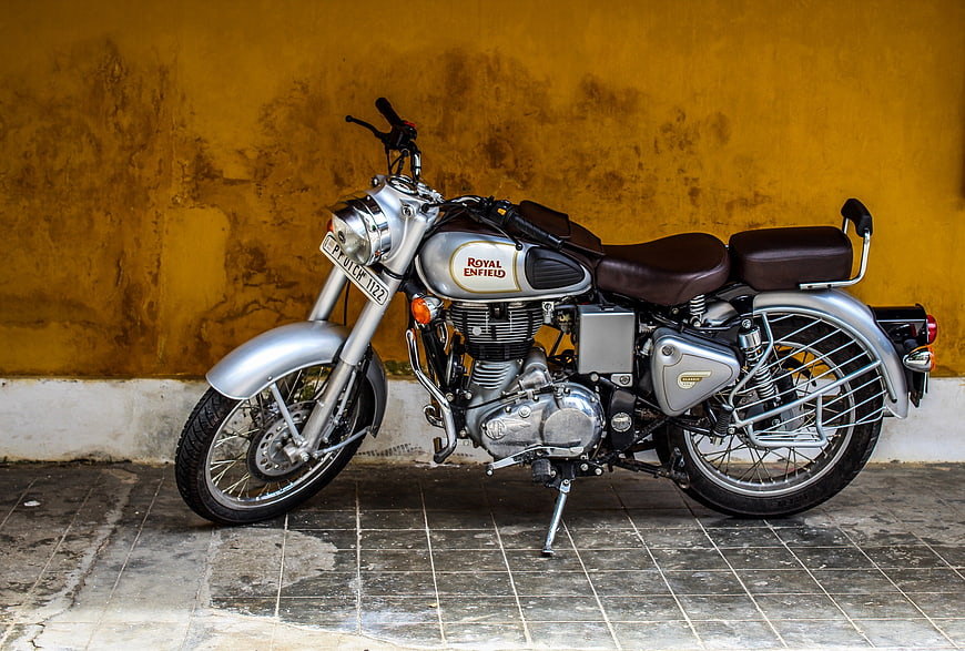 Silver Royal Enfield Classic 350 Motorcycle Against Yellow Wall