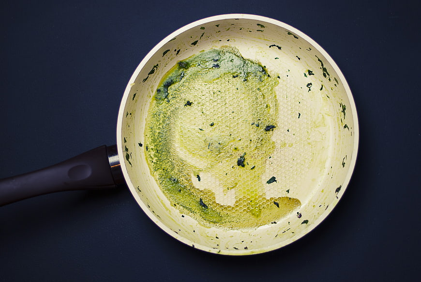 Top view of frying pan with melted green herb butter