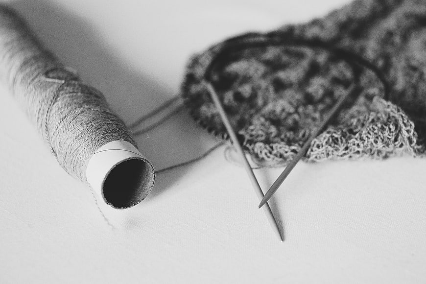 Black and white knitting needles and yarn spool on white background