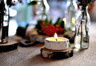 Rustic Tea Light Candle On Wood Slice With Blurred Floral Background