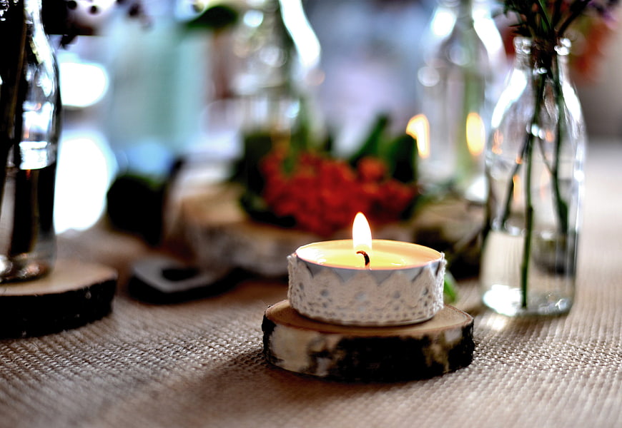 Rustic Tea Light Candle On Wood Slice With Blurred Floral Background