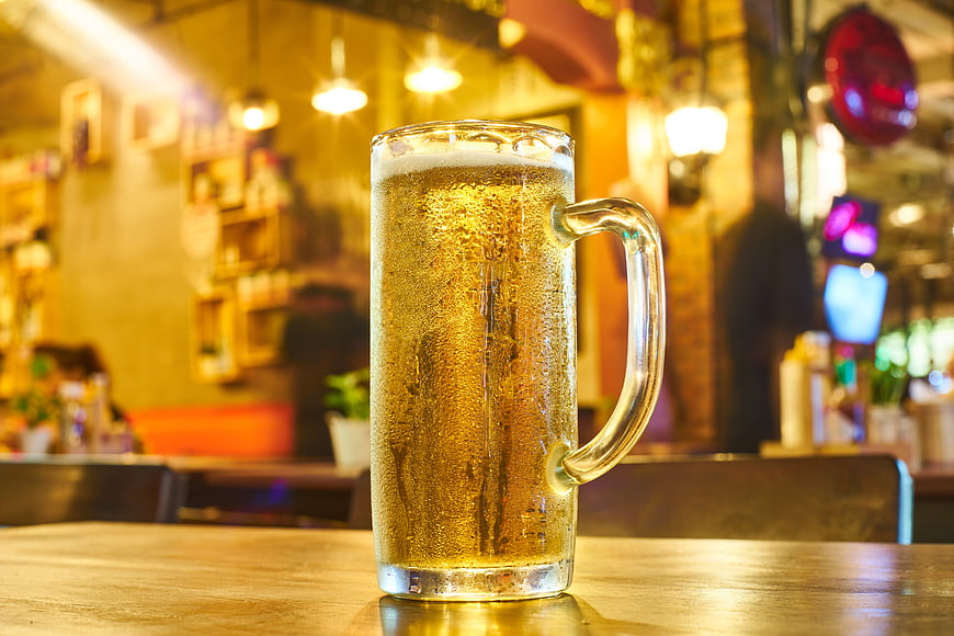 Cold Beer Mug On Wooden Table In Warm Bar Setting