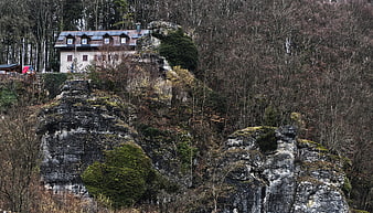 House on rocky cliff in forest landscape