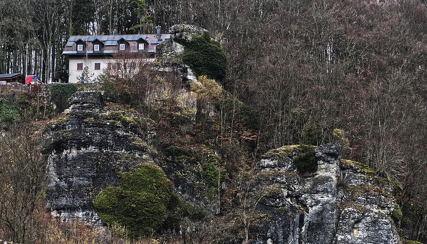 House on rocky cliff in forest landscape