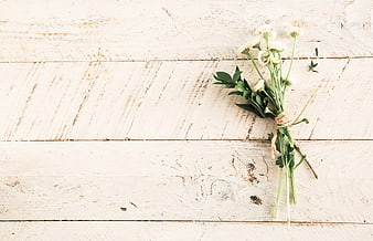 White wildflowers tied with twine on rustic wooden background