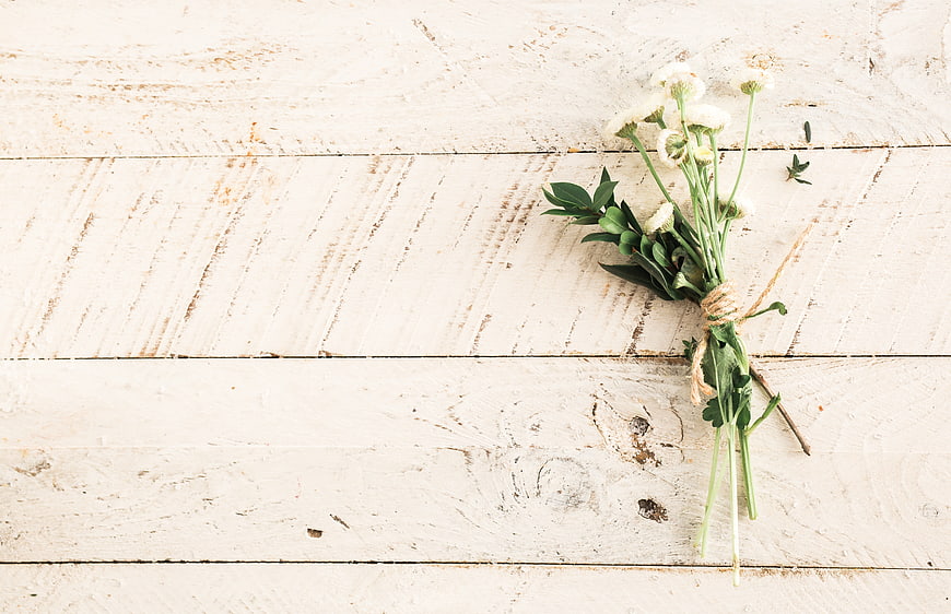 White wildflowers tied with twine on rustic wooden background