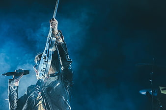 Rock singer holding electric guitar up on stage