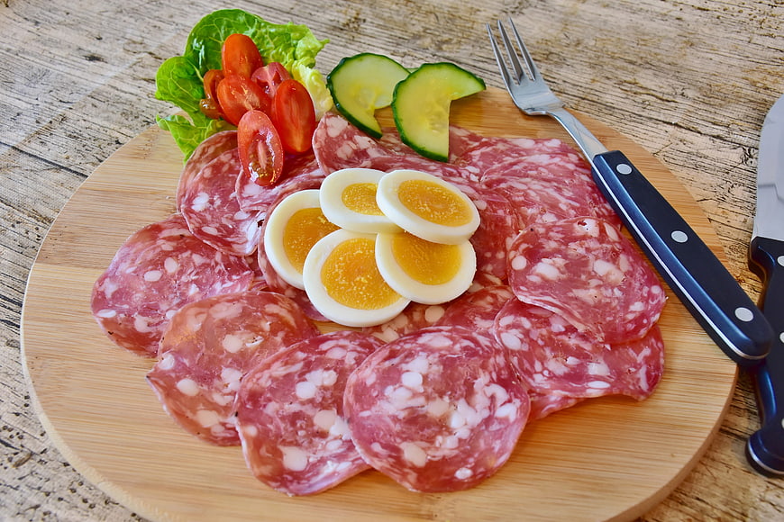 Salami Platter With Boiled Eggs, Tomatoes, And Cucumbers On Wooden Board
