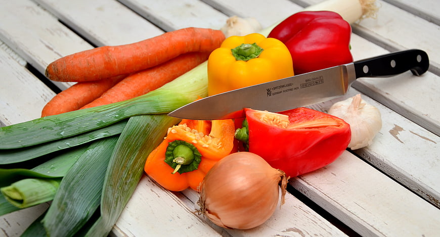 Fresh vegetables and chef knife on rustic white wooden table