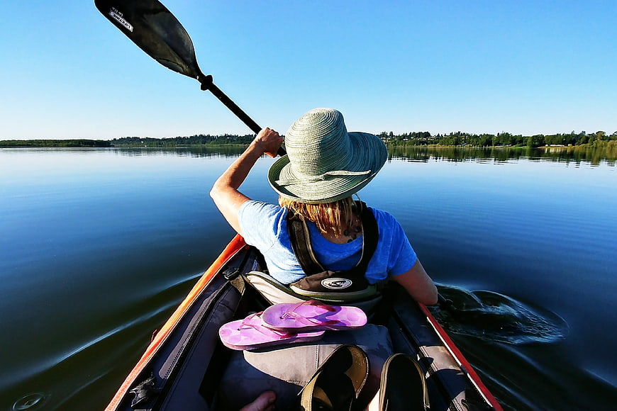 Woman Kayaking on Calm Lake with Paddle