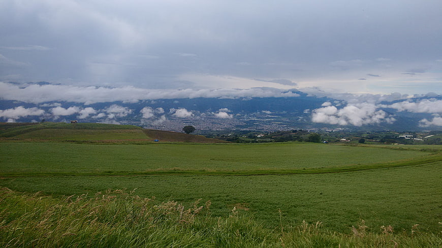 Panoramic green pasture landscape with distant city and mountains