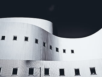 Modern white curved building facade with dark sky