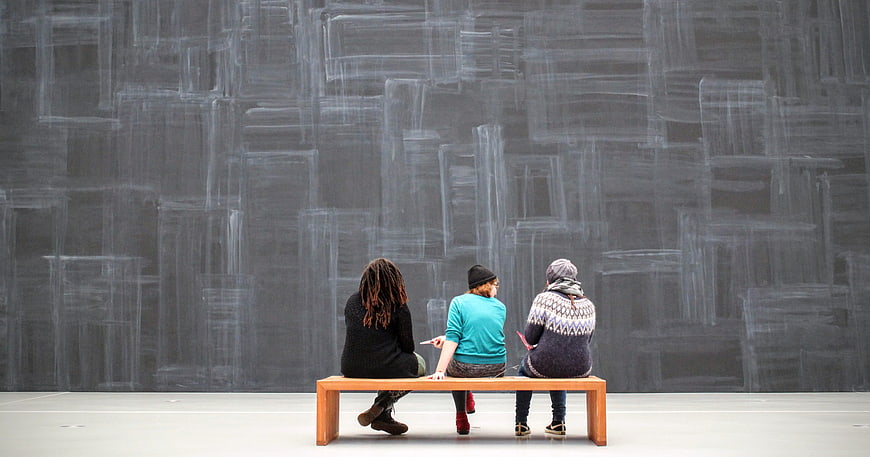 Three people viewing large chalk art installation in gallery
