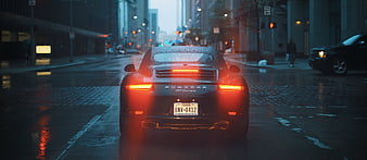 Rear view of Porsche 911 on wet city street at dusk